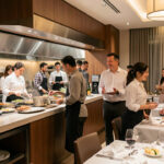 Équipe diversifiée composée de femmes et d’hommes travaillant ensemble dans la cuisine, l’accueil et le service d’un hôtel-restaurant moderne.